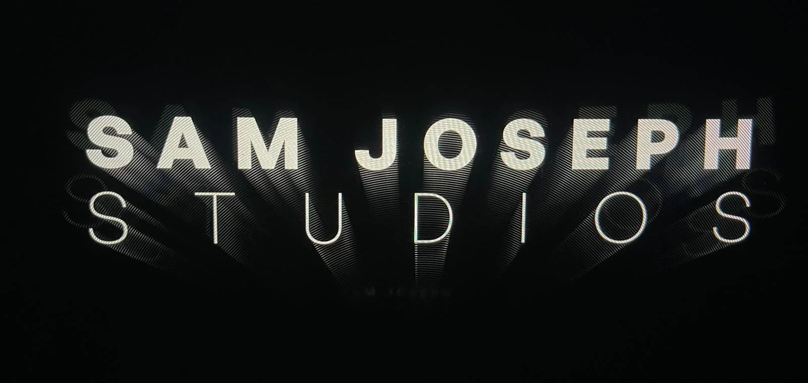 Neon sign reading 'Sam Joseph Studios' in white lettering on a dark background.