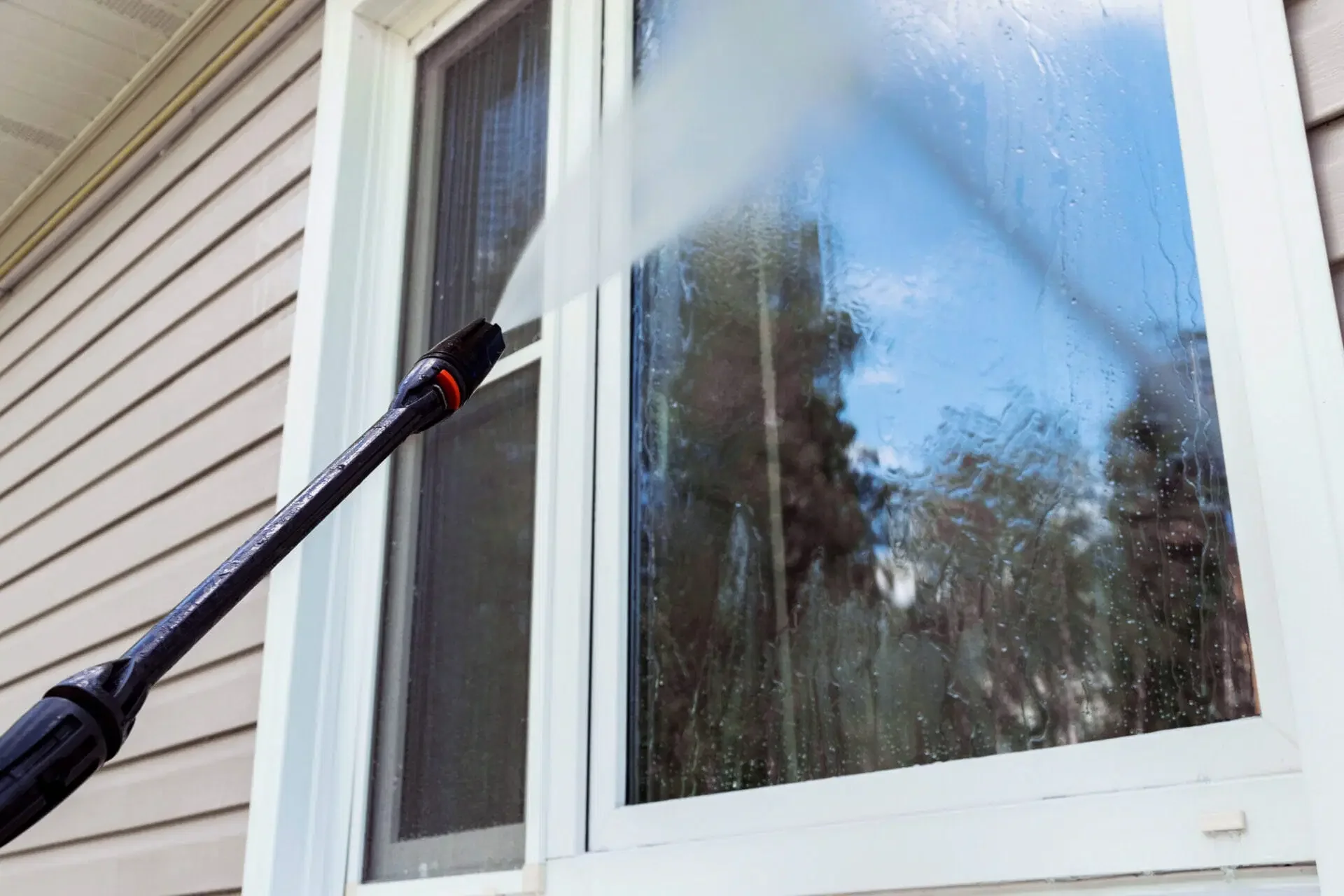 Person cleaning a window with a pressure washer.