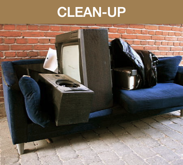 A messy collection of old electronics, including a TV, a speaker, and a stereo, piled on a blue sofa against a brick wall, with a "CLEAN-UP" sign at the top.