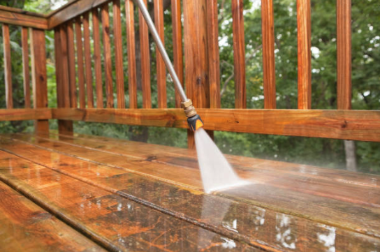 A power washing wand cleaning a wet wooden deck with a jet of water.