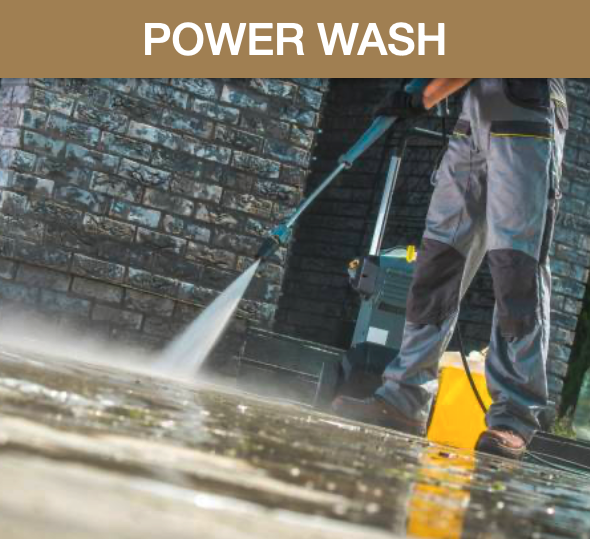 Person power washing a brick wall with a pressure washer, water spray creating a mist on the wet surface.