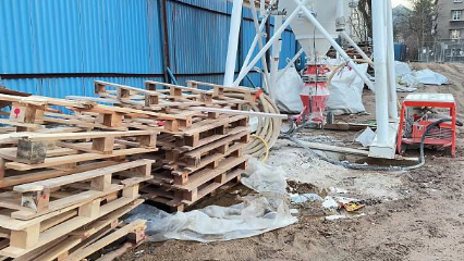 Construction site with wooden pallets, scaffolding, and construction equipment