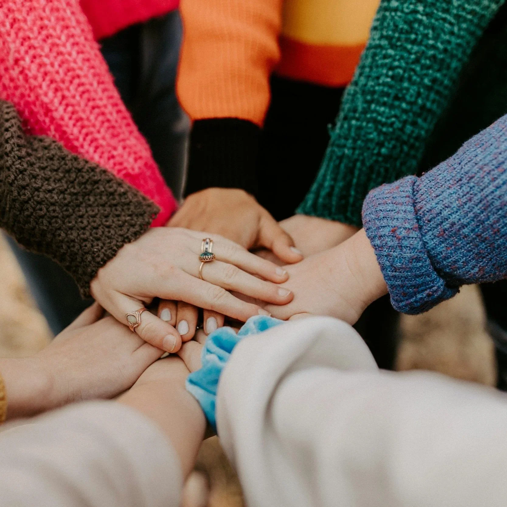 Multiple hands stacked together in a show of unity.