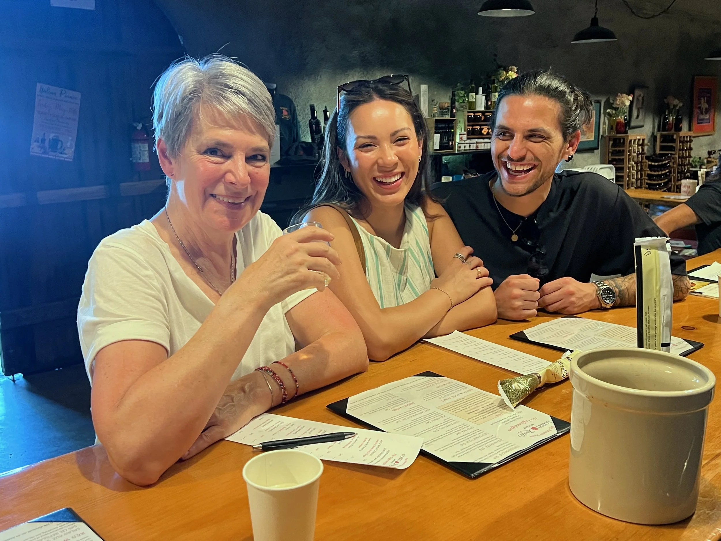 Three people standing at tasting bar, smiling and enjoying their time together.