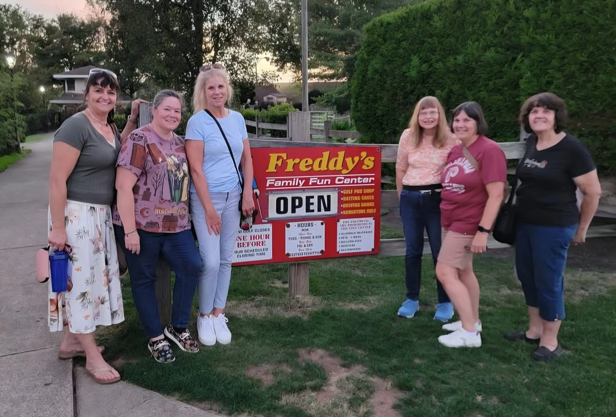 Six women standing in front of a sign for Freddy's Family Fun Center, smiling for the photo.