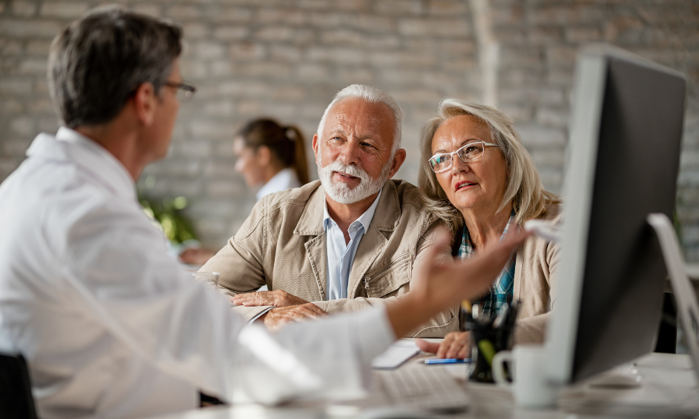 Doctor explaining something to an elderly couple in a medical consultation room.