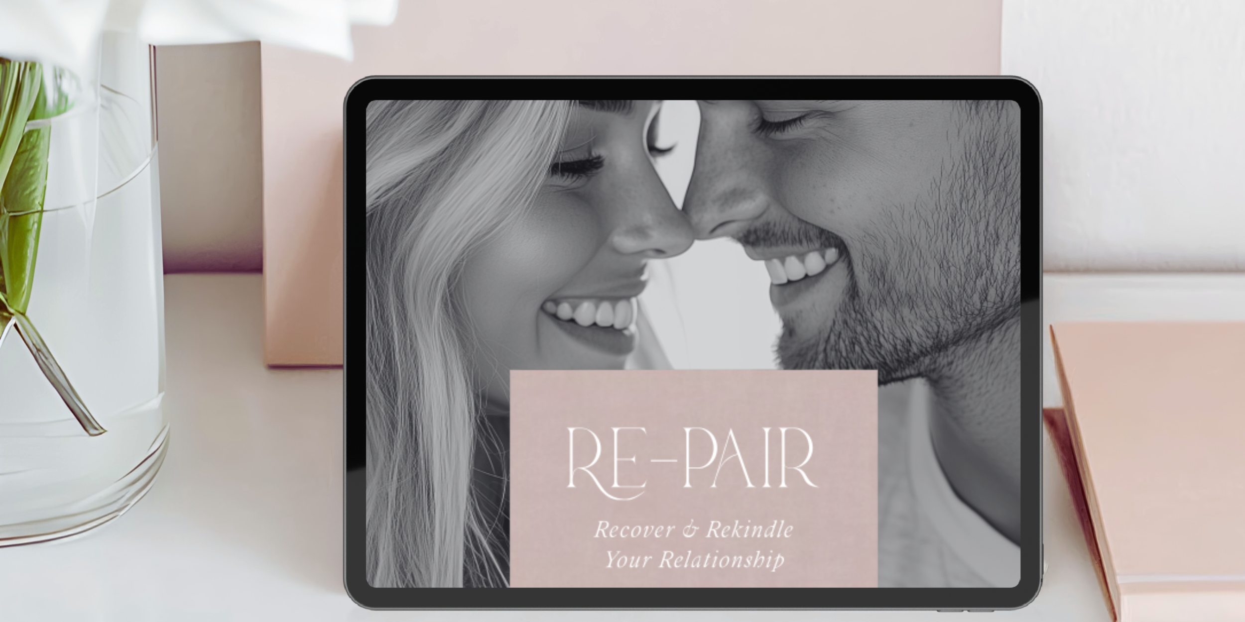 Table with a tablet displaying a black-and-white photo of a smiling couple with foreheads touching and the text 'RE-PAIR: Recover & Rekindle Your Relationship'.