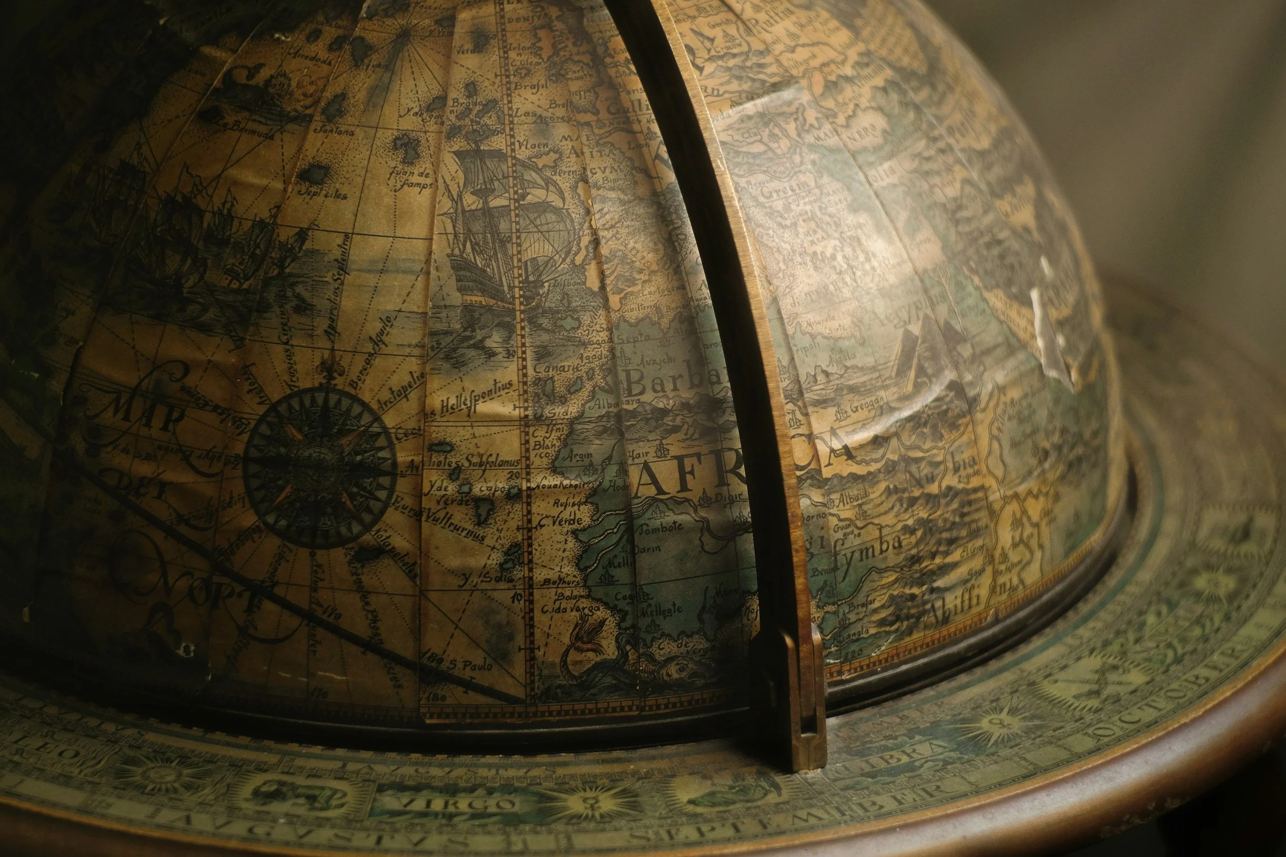 Close-up of a vintage globe with an antique map showing continents, oceans, and ships.