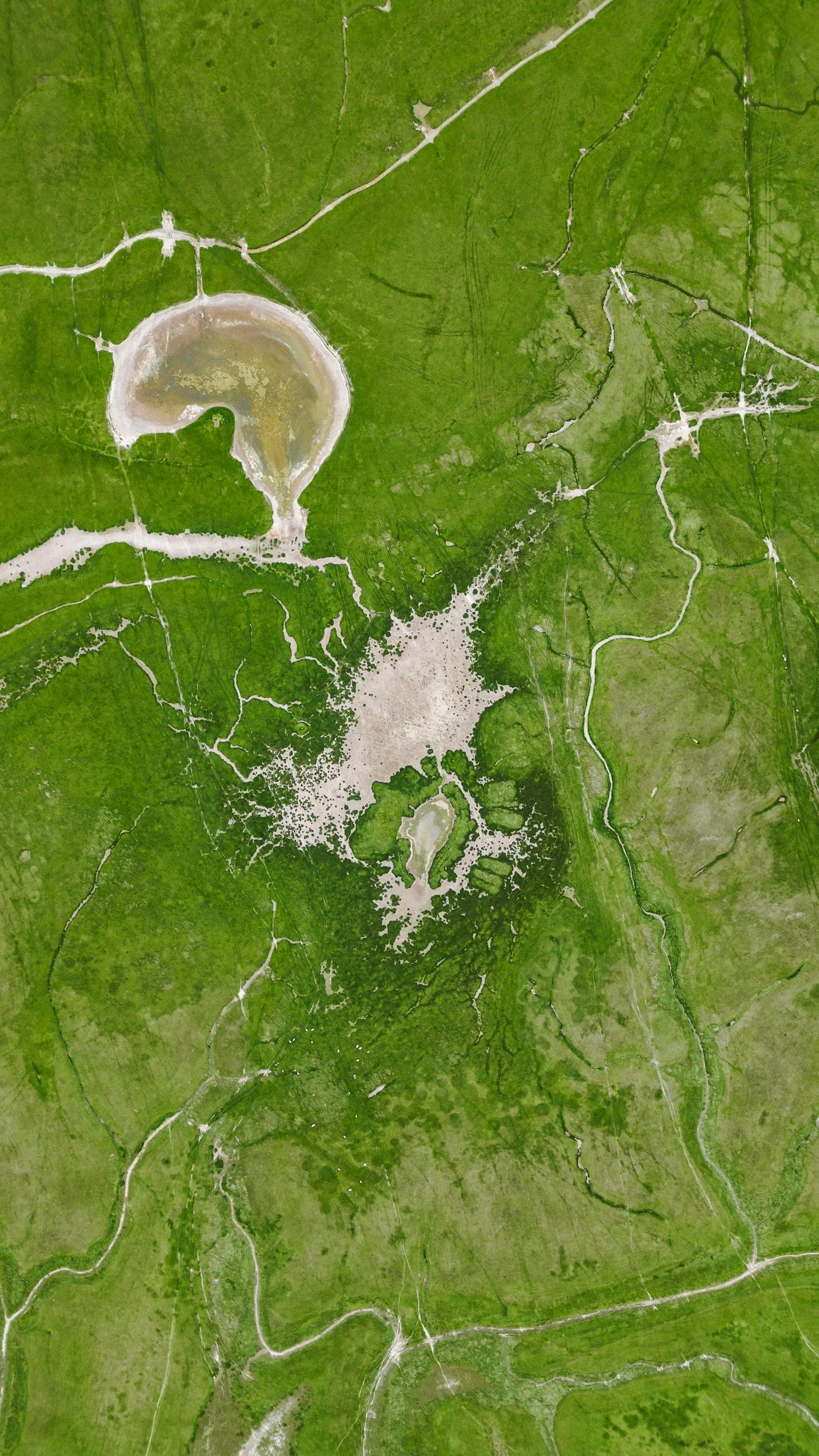 Aerial view of a valley with lakes, roads, and green fields.