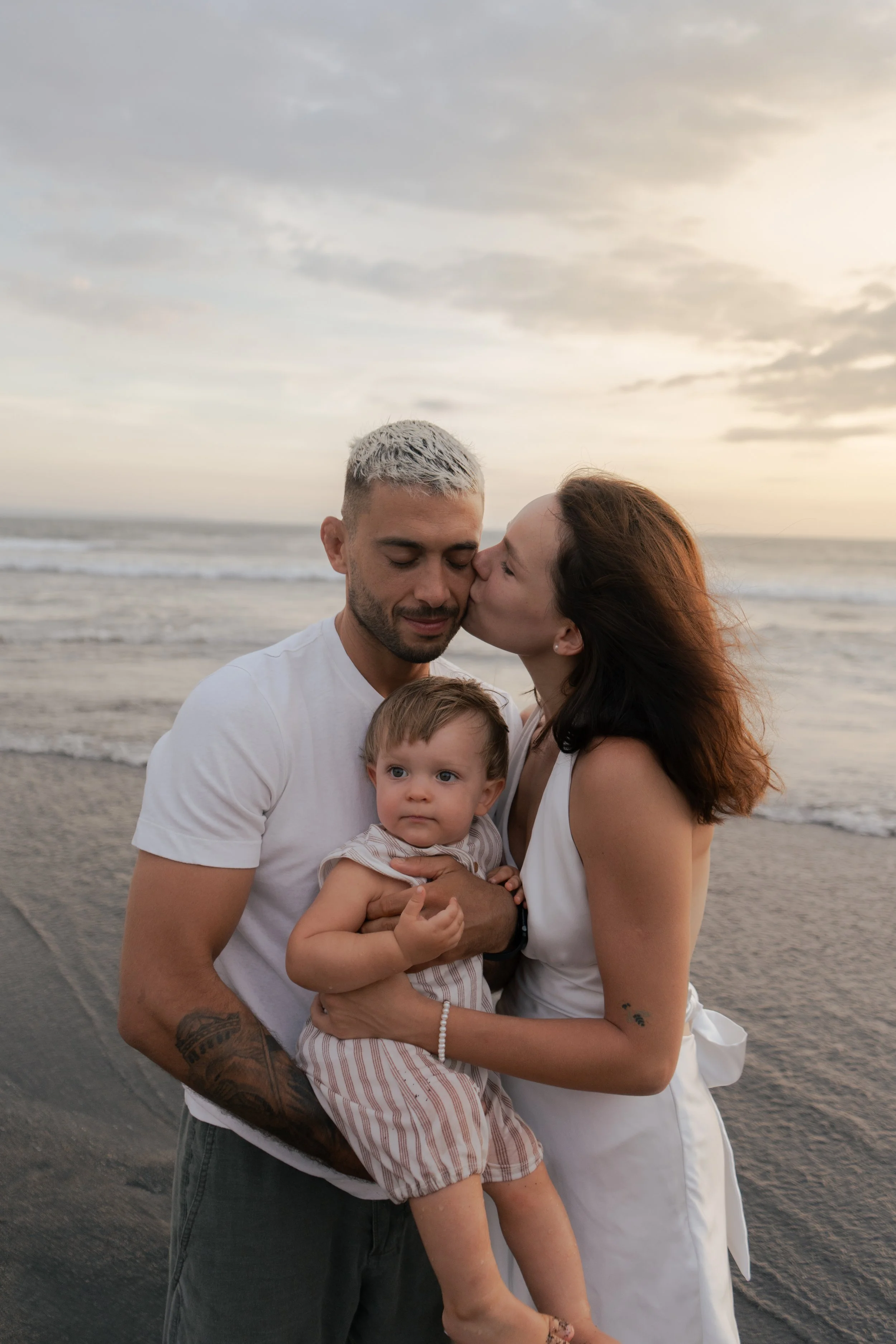 Family embracing on the beach during a candid family photography session with movement and connection