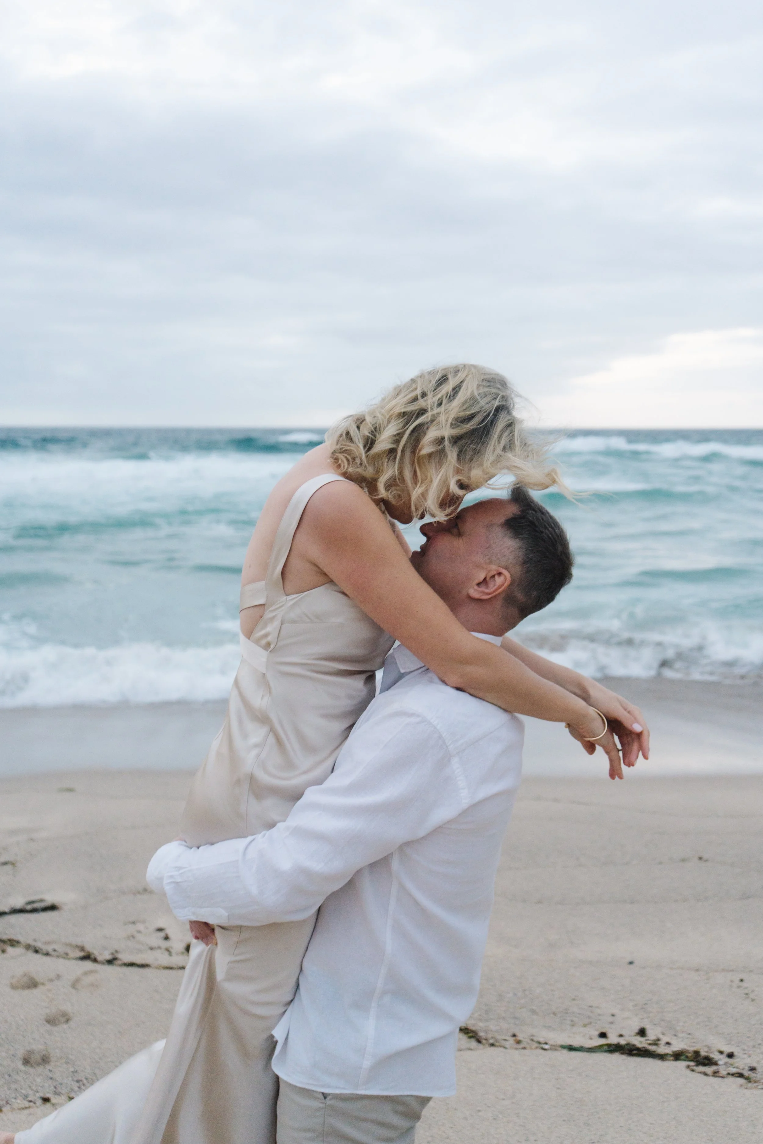 Couple lifting fiancee on the beach during a relaxed and natural engagement photography session