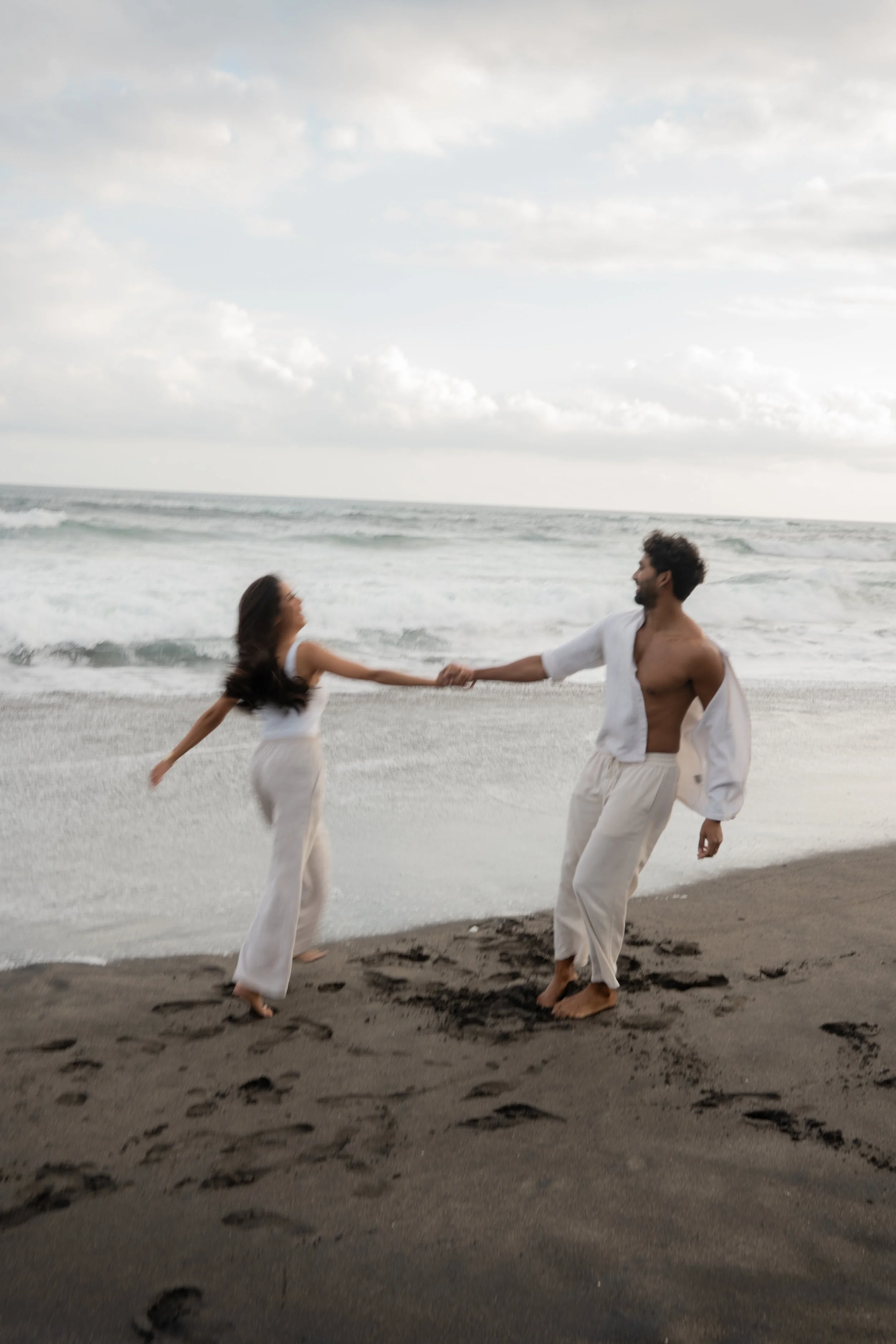 Couple spinning together on the beach, captured with motion blur for an expressive and romantic couples photography moment