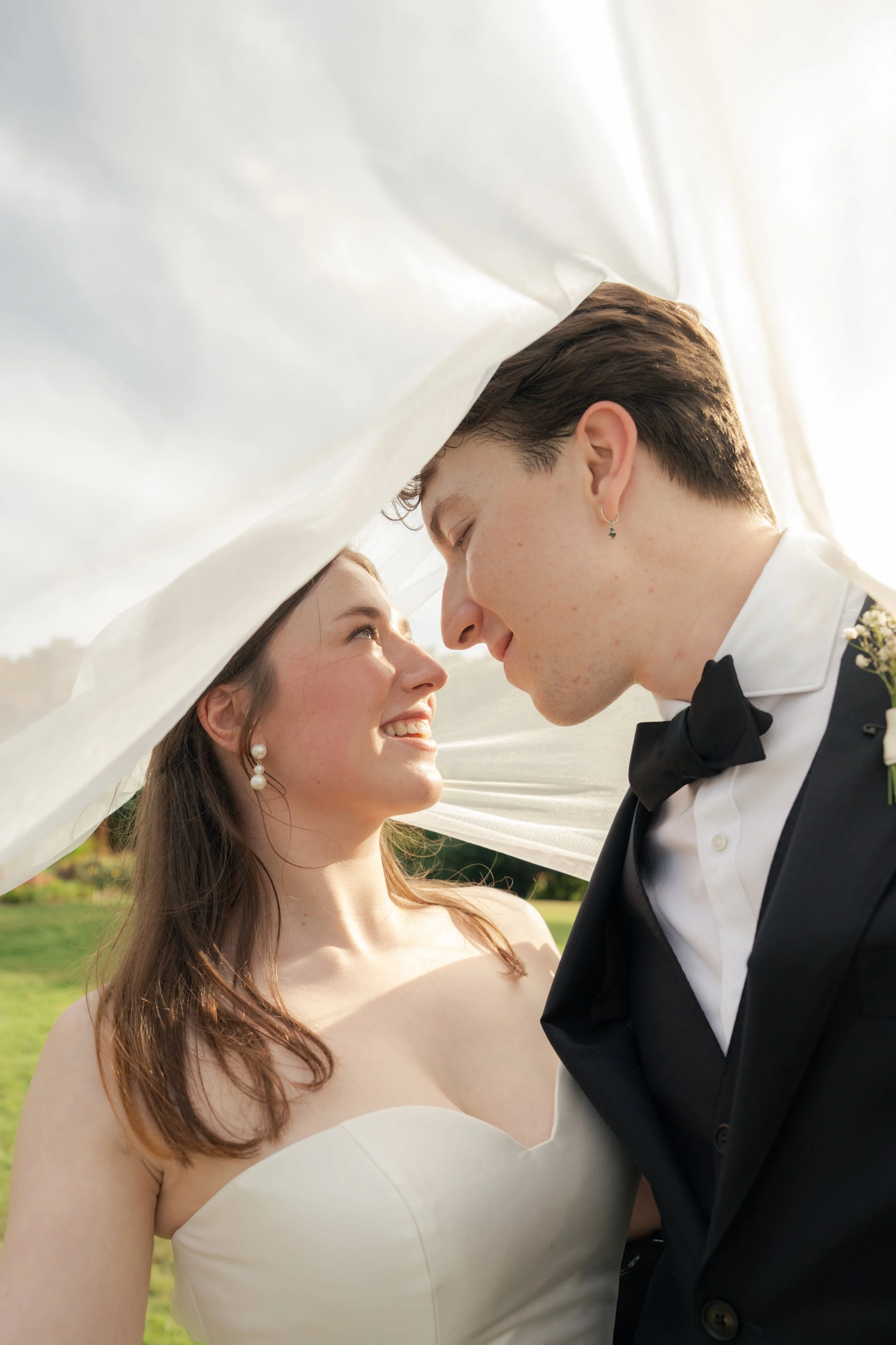 bride and groom in the sun looking into each others eyes under bride's veil