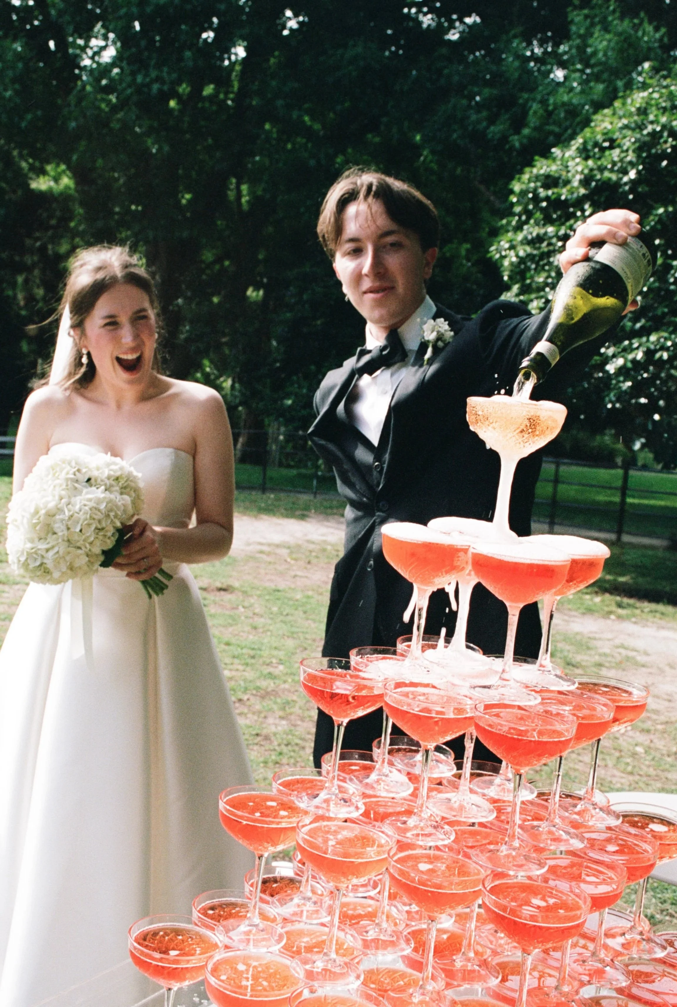 Bride and groom pouring champagne after their wedding ceremony, photographed on film by a natural wedding photographer