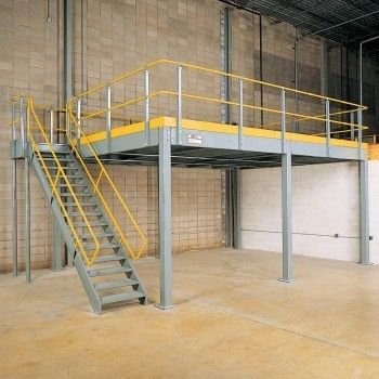 Elevated warehouse platform with yellow safety railings and stairs inside an industrial building.