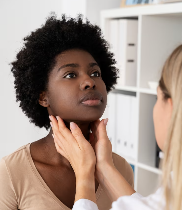 A healthcare professional examining a woman by gently holding her neck and inspecting her throat.