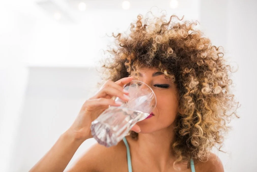woman drinking water to increase hydration as a pelvic and sexual health goal/habit