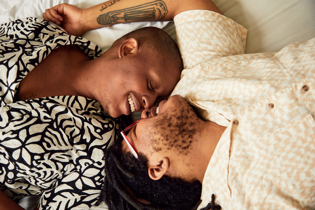 Couple smiling together while being intimate because they have increased their intimacy communication skills, address low libido, released pain with sex, and found pleasure in sex.