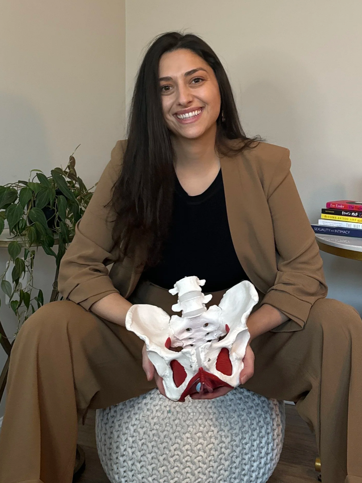 Gina, a pelvic floor therapist, smiling holding a pelvic model. She's a pelvic floor therapy clinic owner in Denver, Colorado for constipation, urinary urgency, pelvic pain, and more.