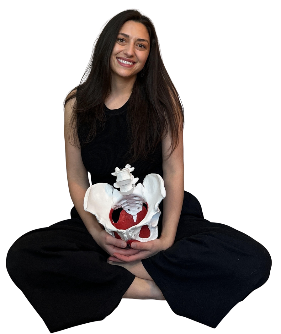 Gina, a Denver pelvic floor therapist, in black clothes holding a pelvic model. She is smiling because she gets to treat pelvic pain, painful sex, vaginismus, constipation, & bladder urgency!
