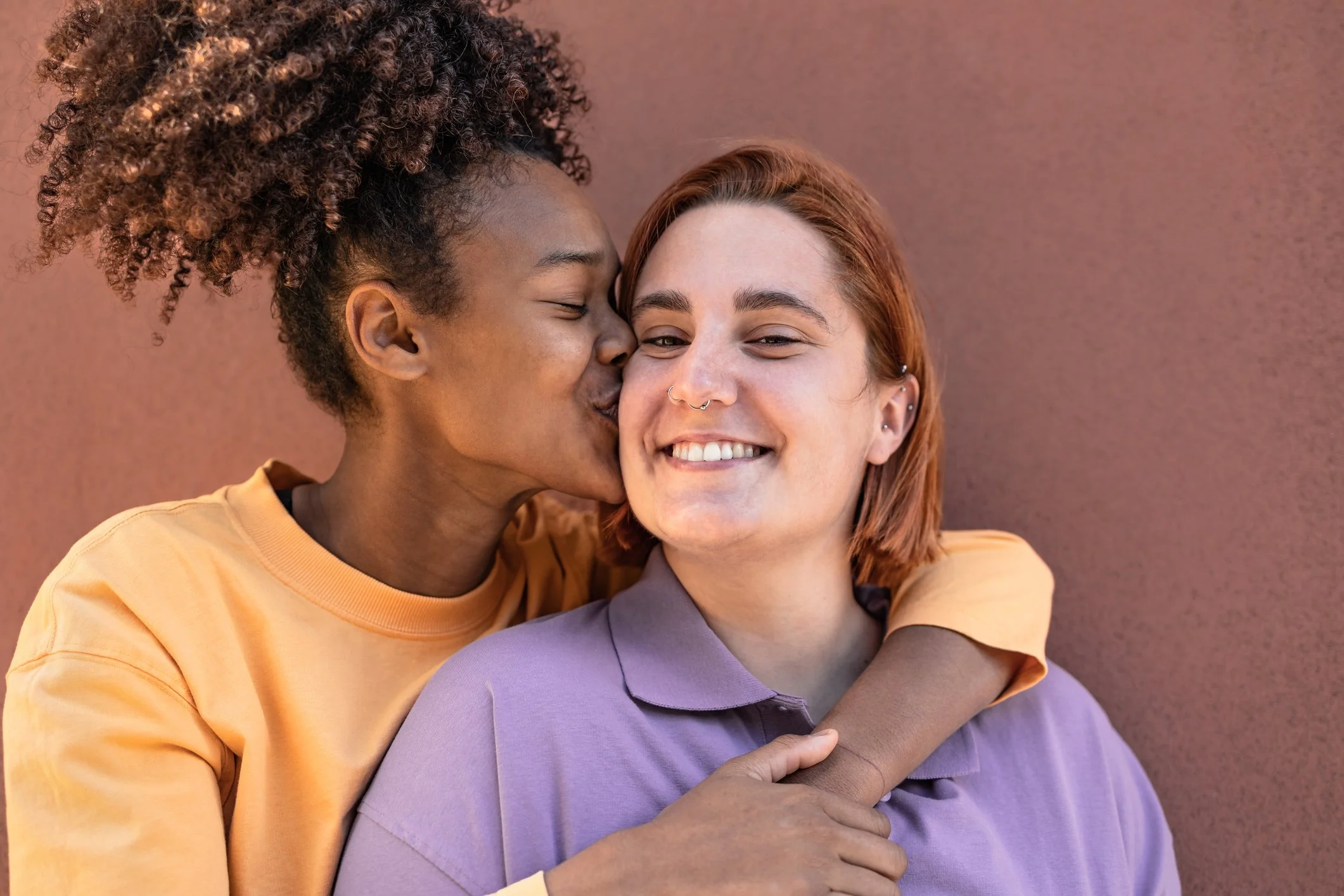 Two women hugging, and one kissing the other because they both optimized their pelvic health and intimacy