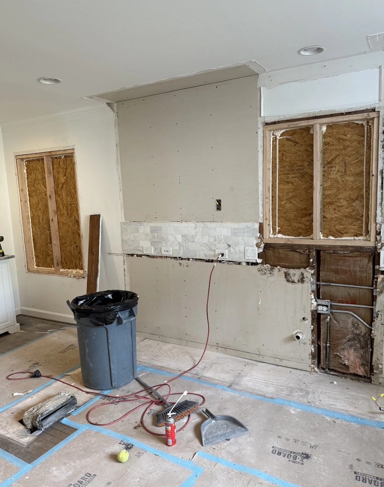Undergoing home renovation with exposed drywall, plywood, and construction tools on the floor.