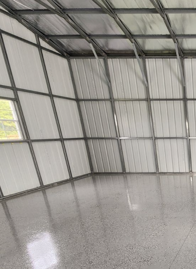 Interior of a metal building with a small window, polished concrete floor, and metal walls and ceiling