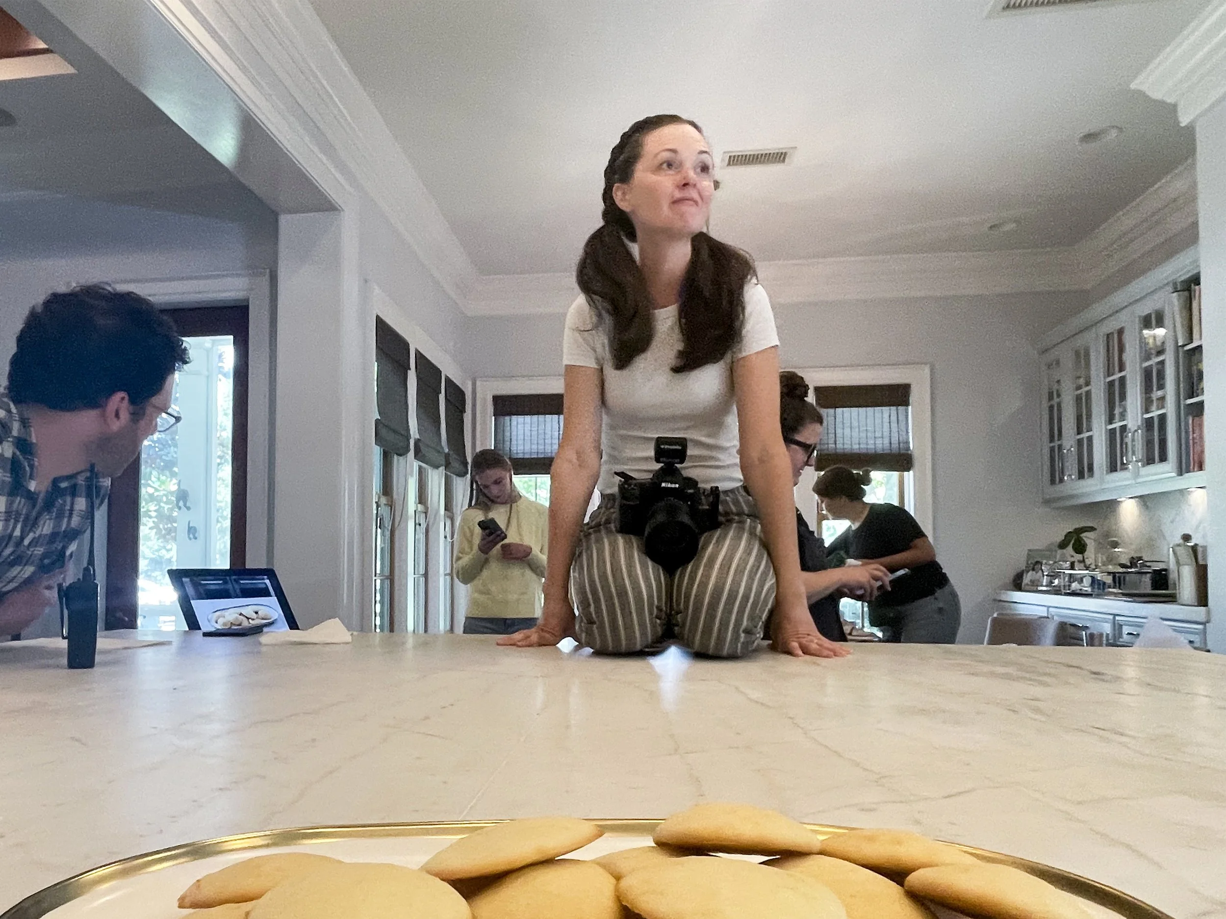 Behind the scenes of Meagan on set sitting on the counter getting just the right angle for an image.