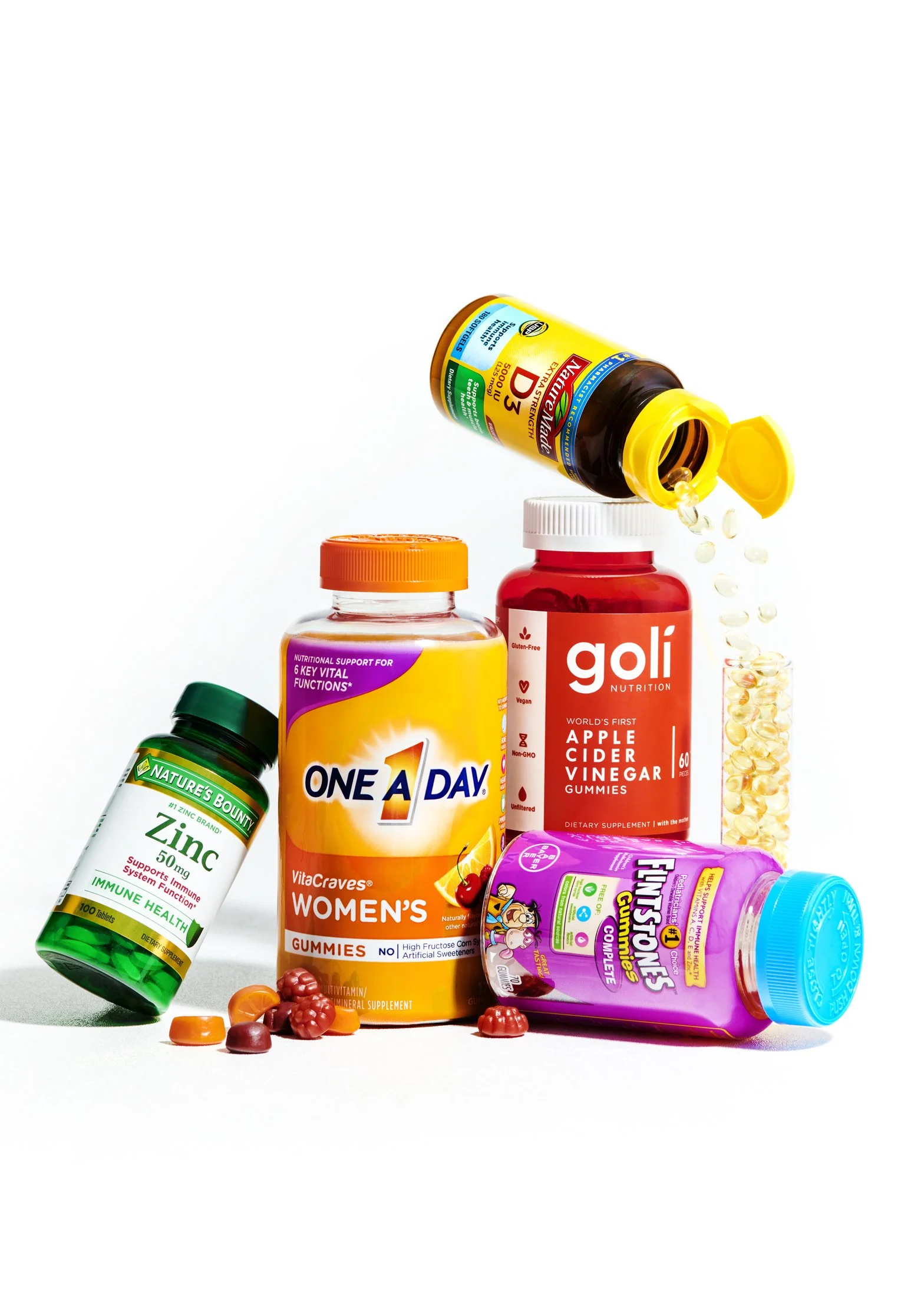 Various dietary supplements and vitamins, including gummies and tablets, arranged on a white background.