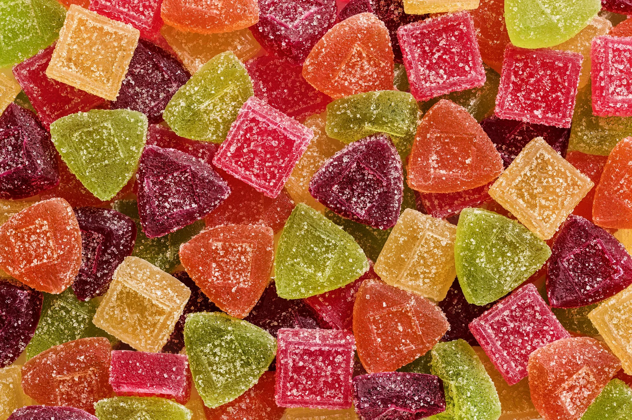 Colorful assorted fruit-flavored gummy candies coated in sugar scattered randomly.
