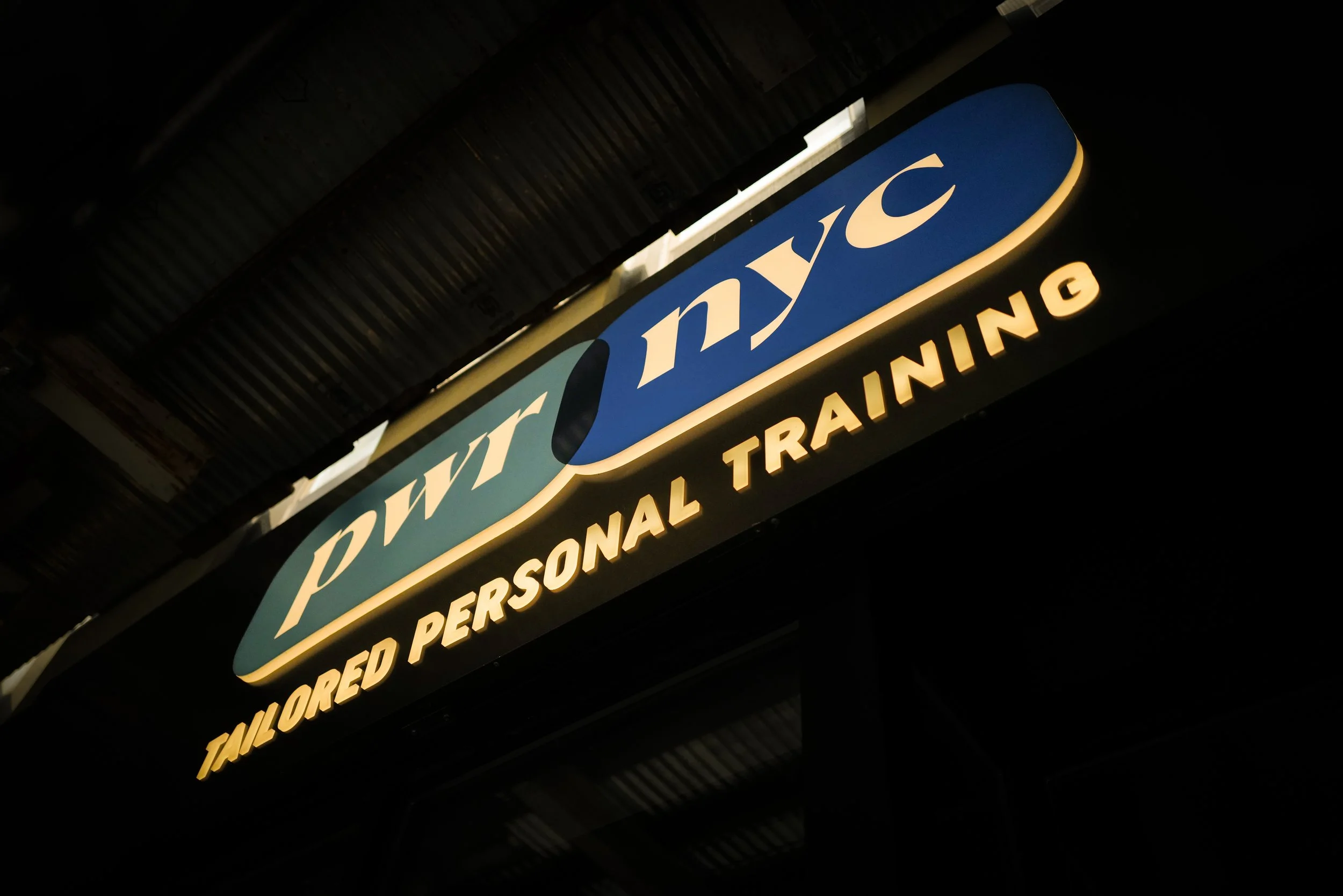 Illuminated sign for duty-free Tanzania store offering tailored personal training, at night.