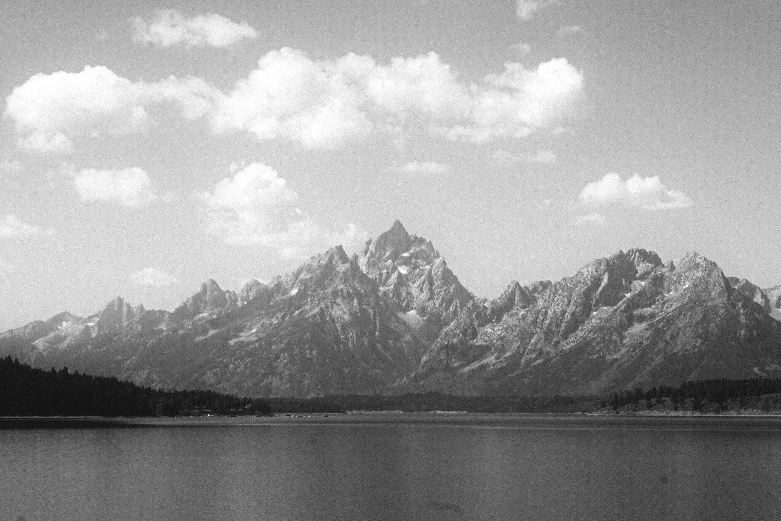 photo of a mountain range with a lake in the foreground and clouds in the sky. professionally take by alpenglow north media.