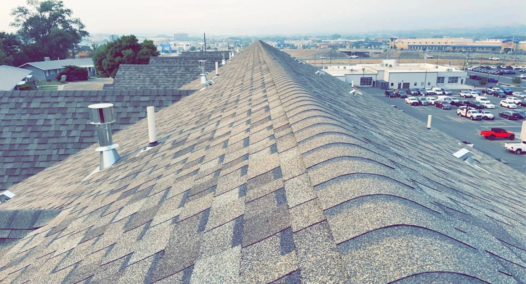 Techo con tejas de grava y ventilaciones en un área urbana.