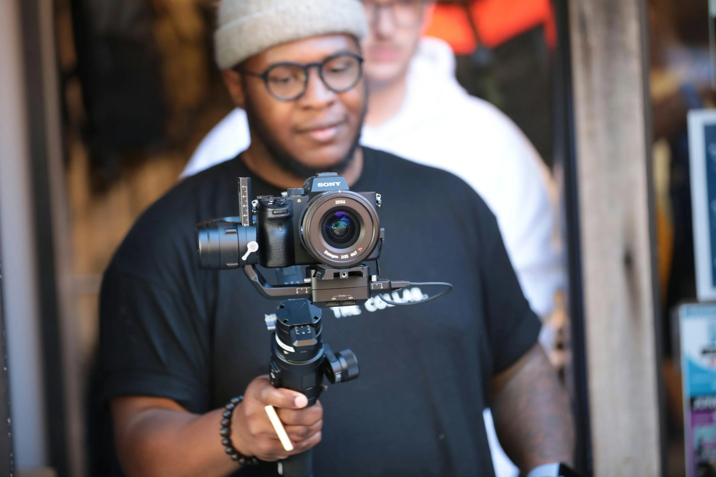 Person holding a professional camera mounted on a stabilizer, with a blurred background.