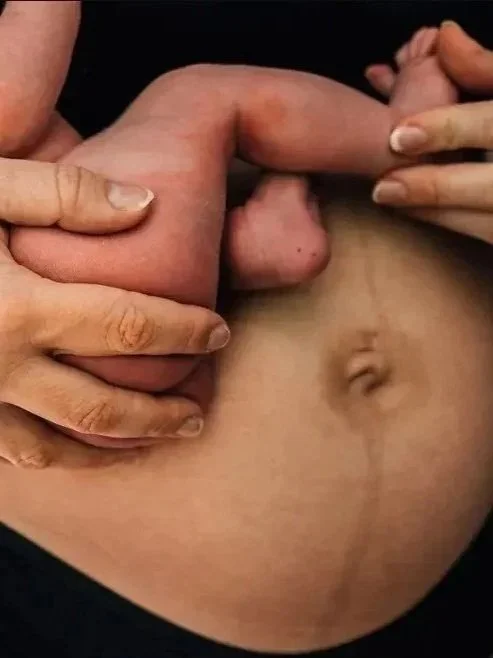 Close-up on mamas belly holding a baby