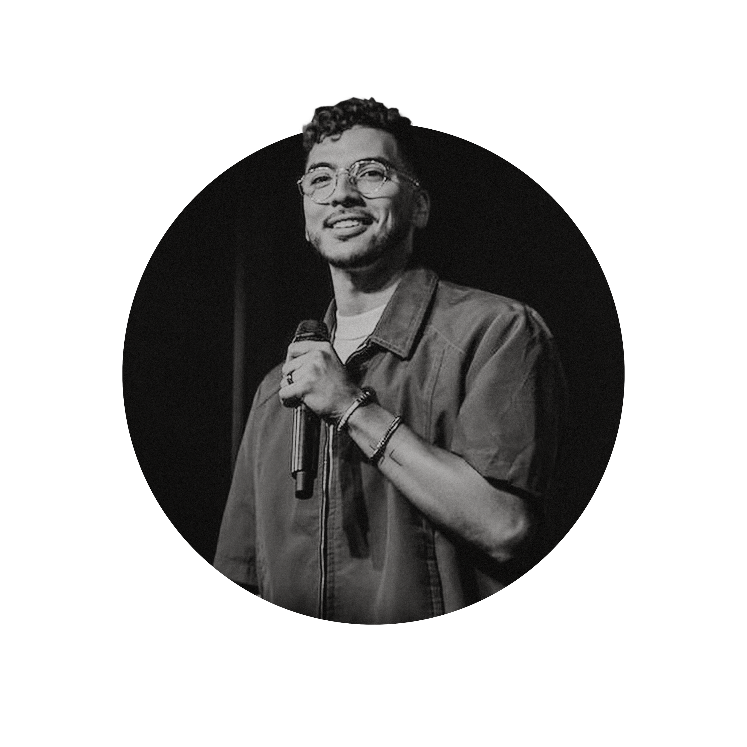 Michael El-Tatrori, Pastor at Church LV, holding a microphone and smiling, speaking on stage in black and white.