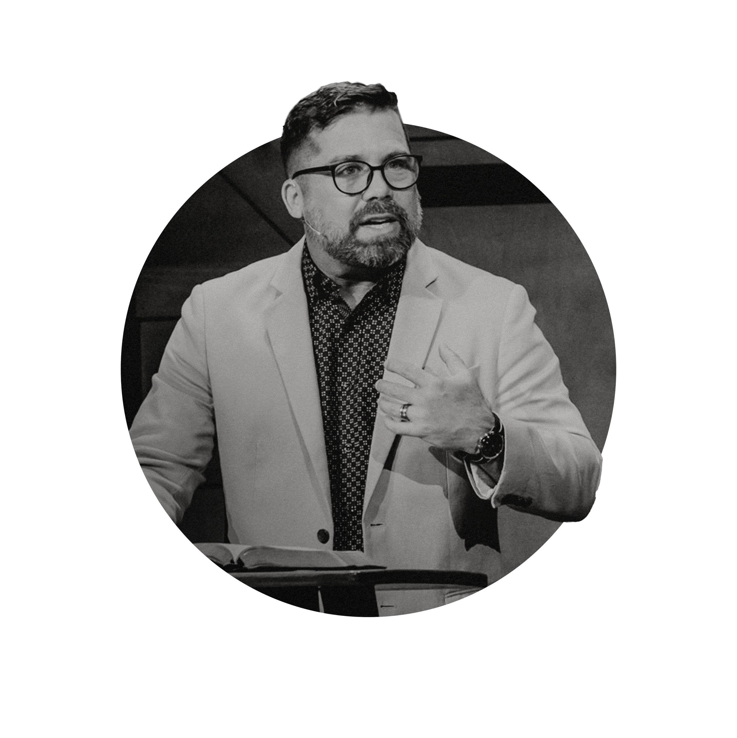 Brian Bowman, Pastor of Valley Life church in Phoenix, Arizona, wearing a white blazer and a patterned shirt, speaking and gesturing with his hand while seated at a table.