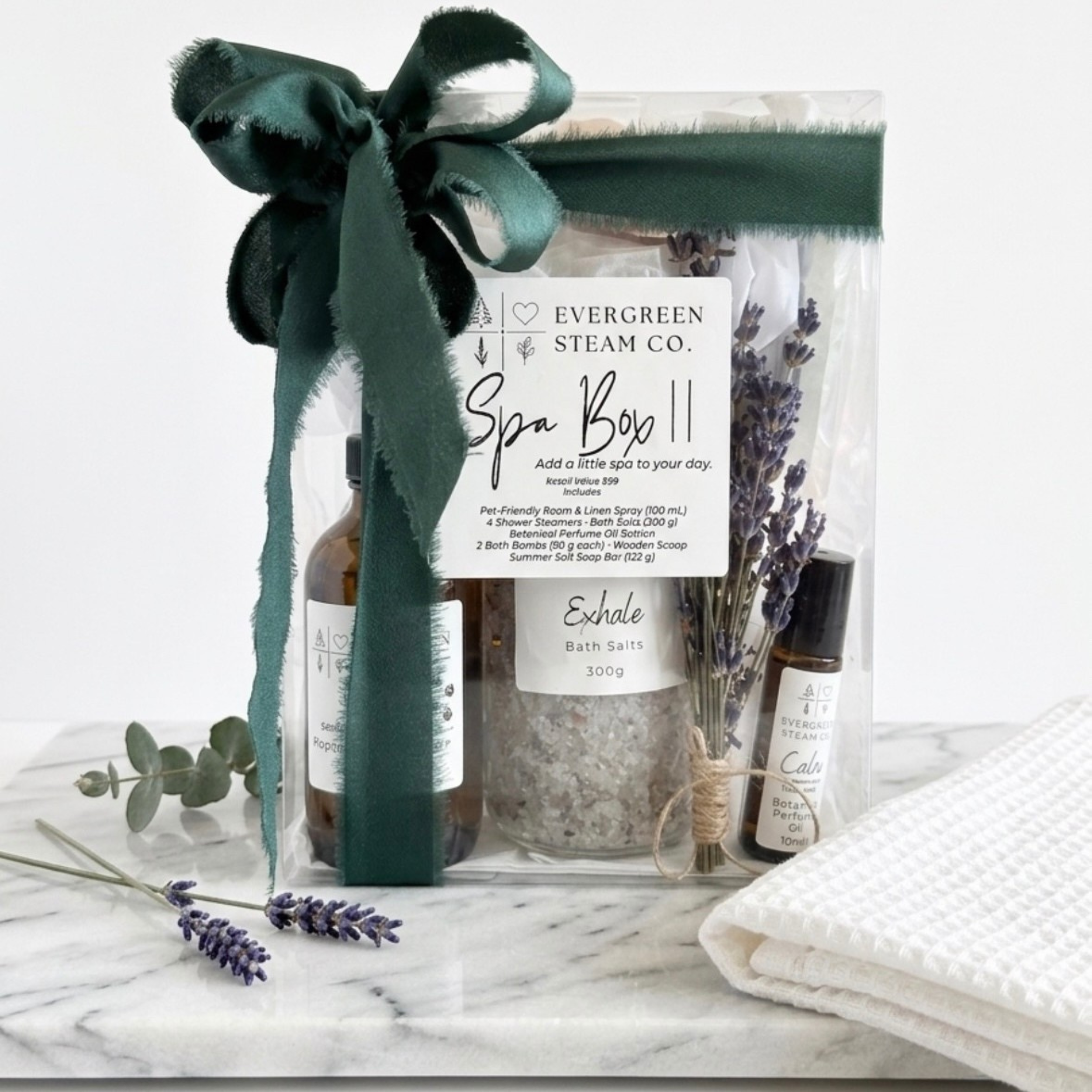 Evergreen Steam Co. Spa Box self-care gift set featuring bath salts and handmade soap, finished with a green ribbon and lavender.