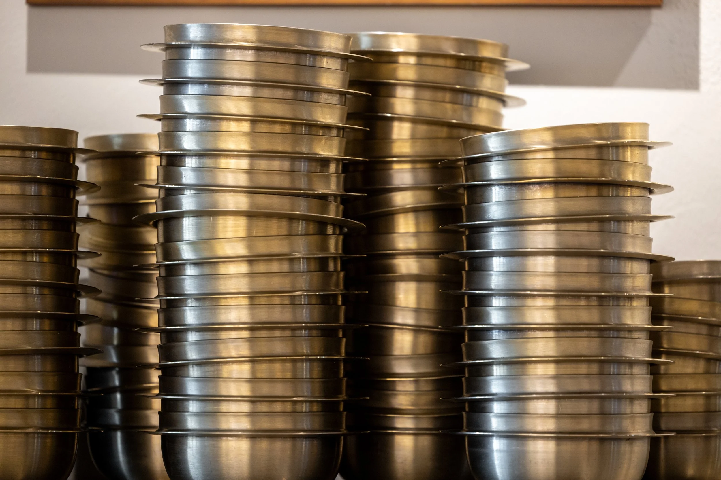 Stacks of metal food serving bowls on a shelf.