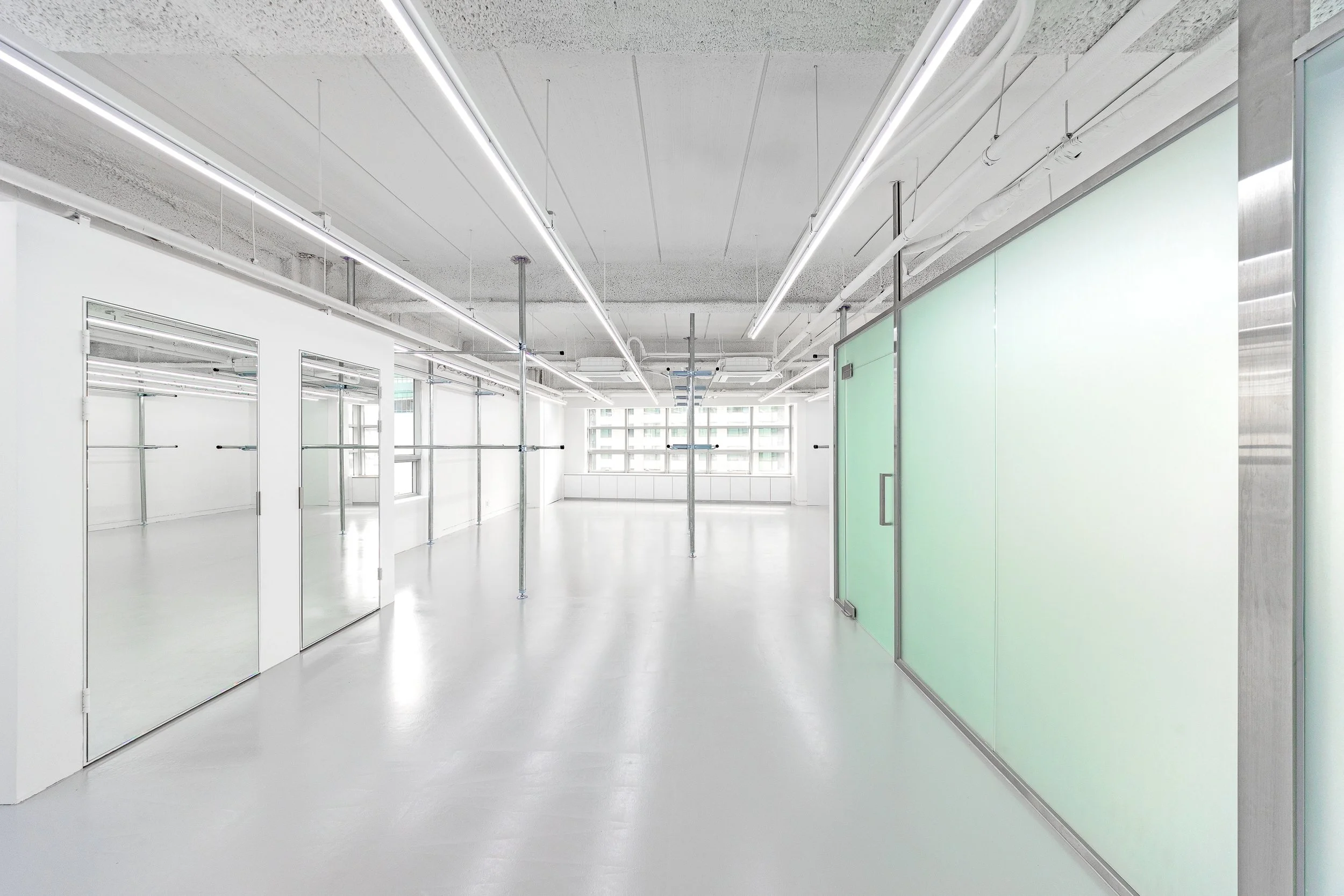 Empty modern room with white floors, white walls, large windows, and construction scaffolding.