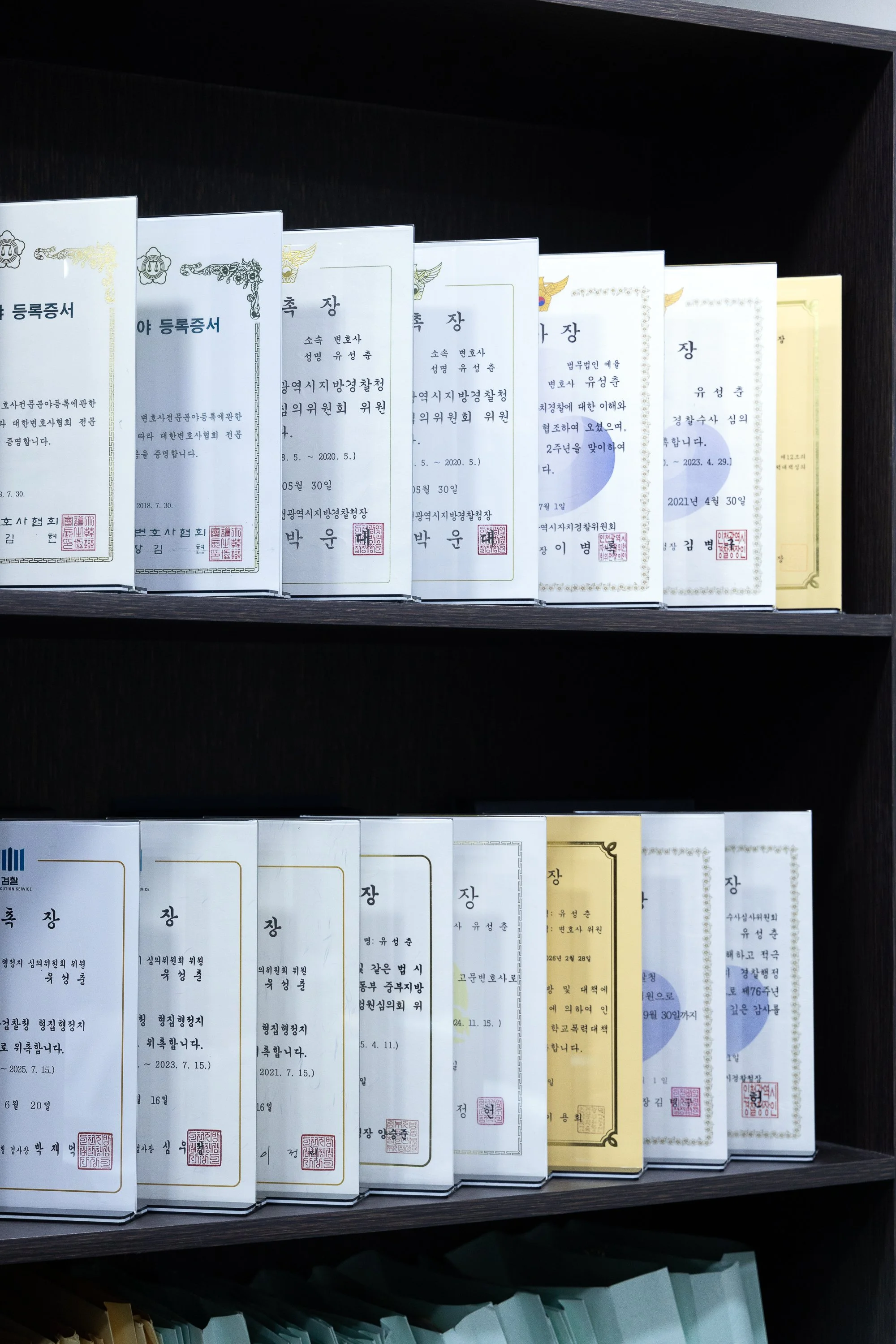 Book shelf with multiple books or certificates in Korean, standing upright.
