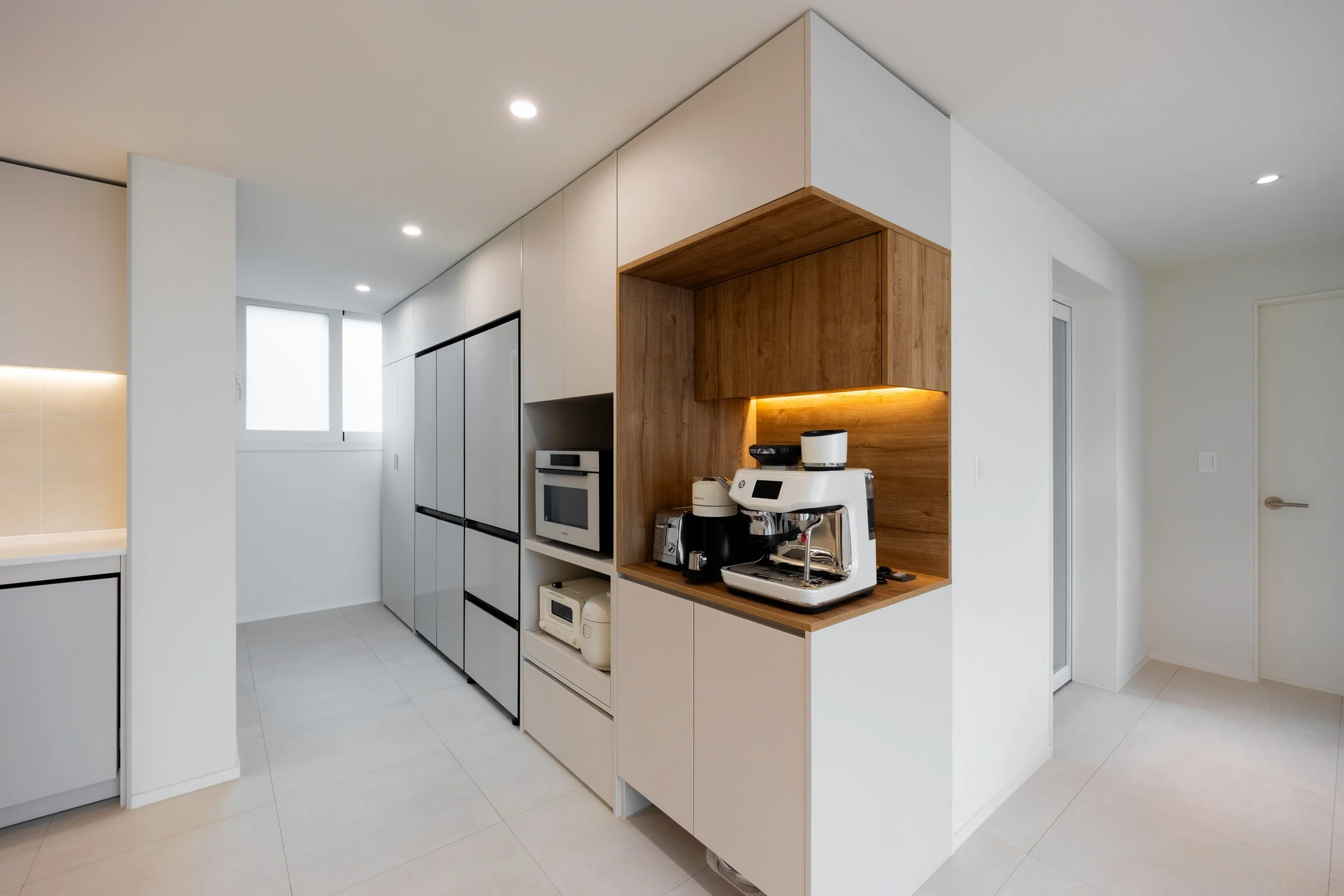 Modern kitchen with white and wood cabinetry, built-in appliances, and a coffee machine on a wooden countertop