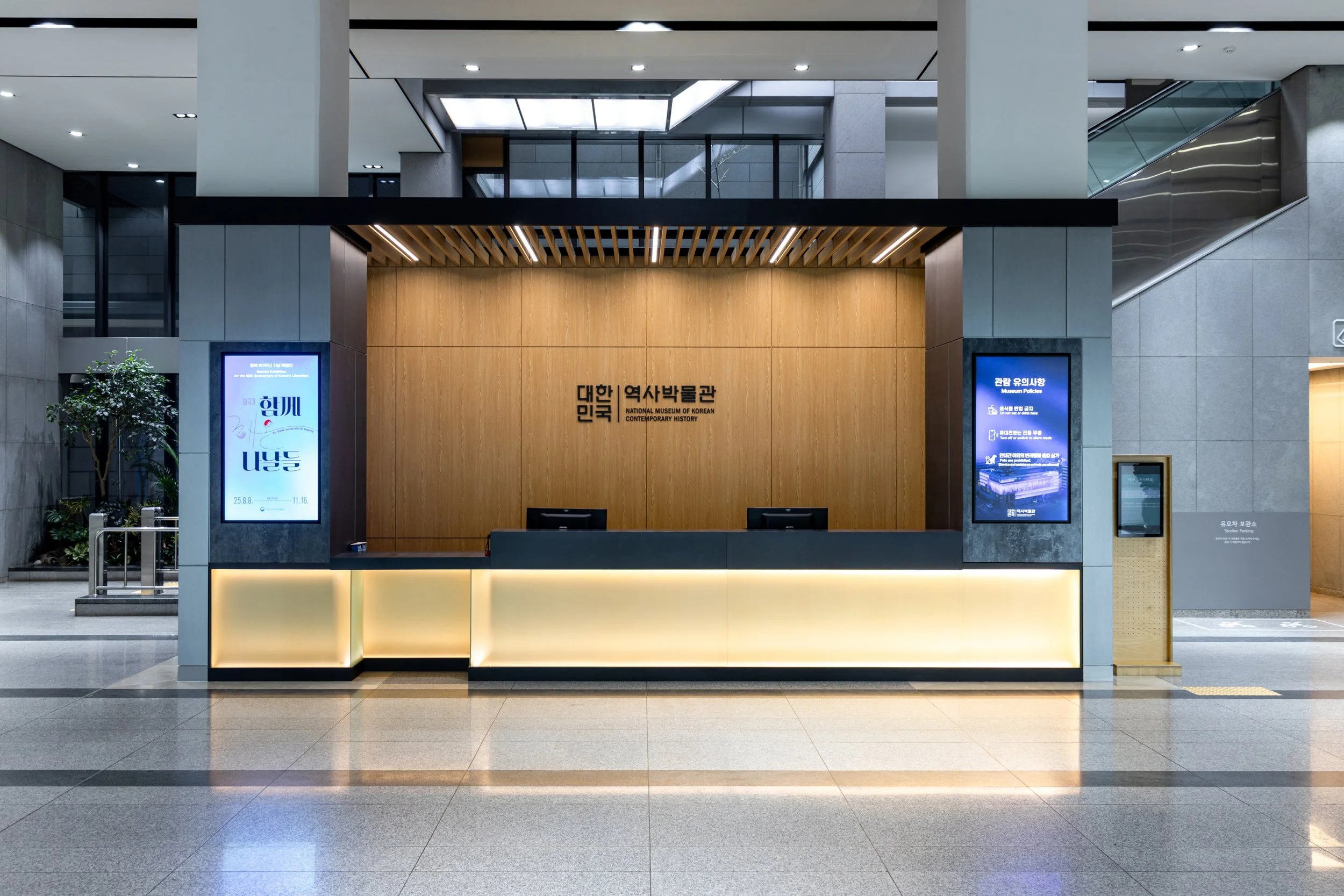 Reception desk at the National Museum of Korean Contemporary History in South Korea, with two digital display screens and a wooden backdrop.
