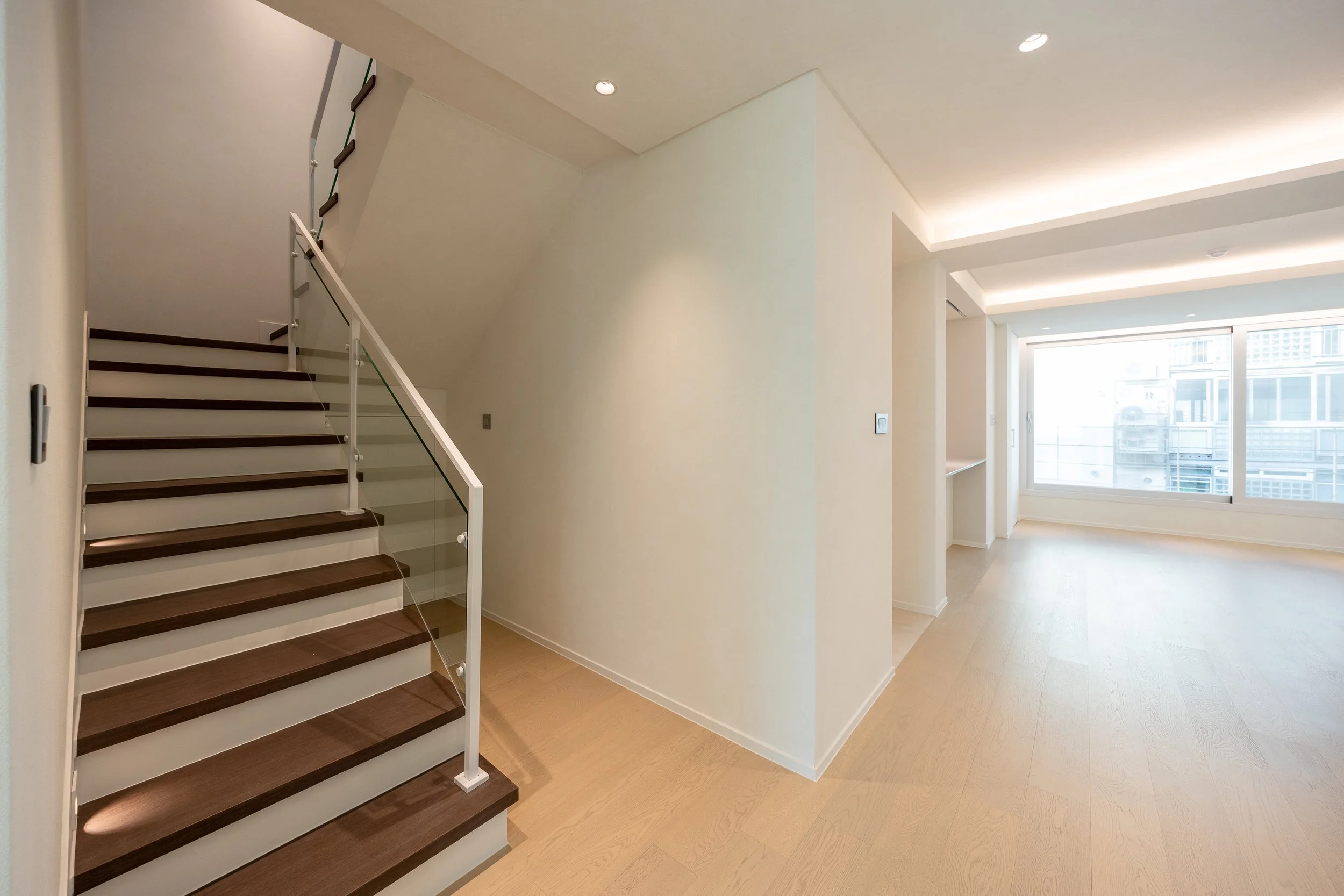 Empty modern apartment interior with staircase and large window.