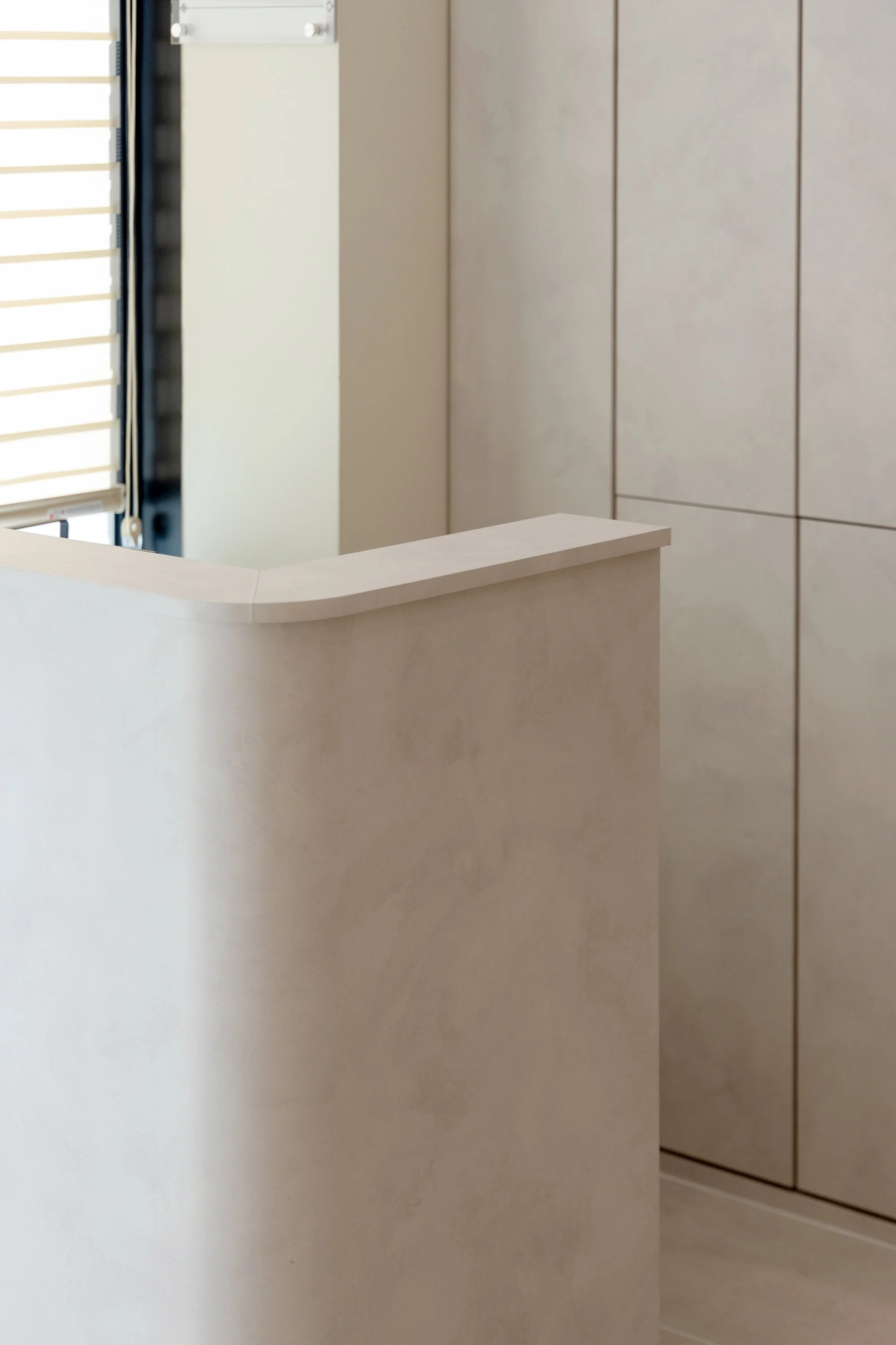 A beige reception desk with a curved corner in front of beige cabinets in an office or clinic setting.