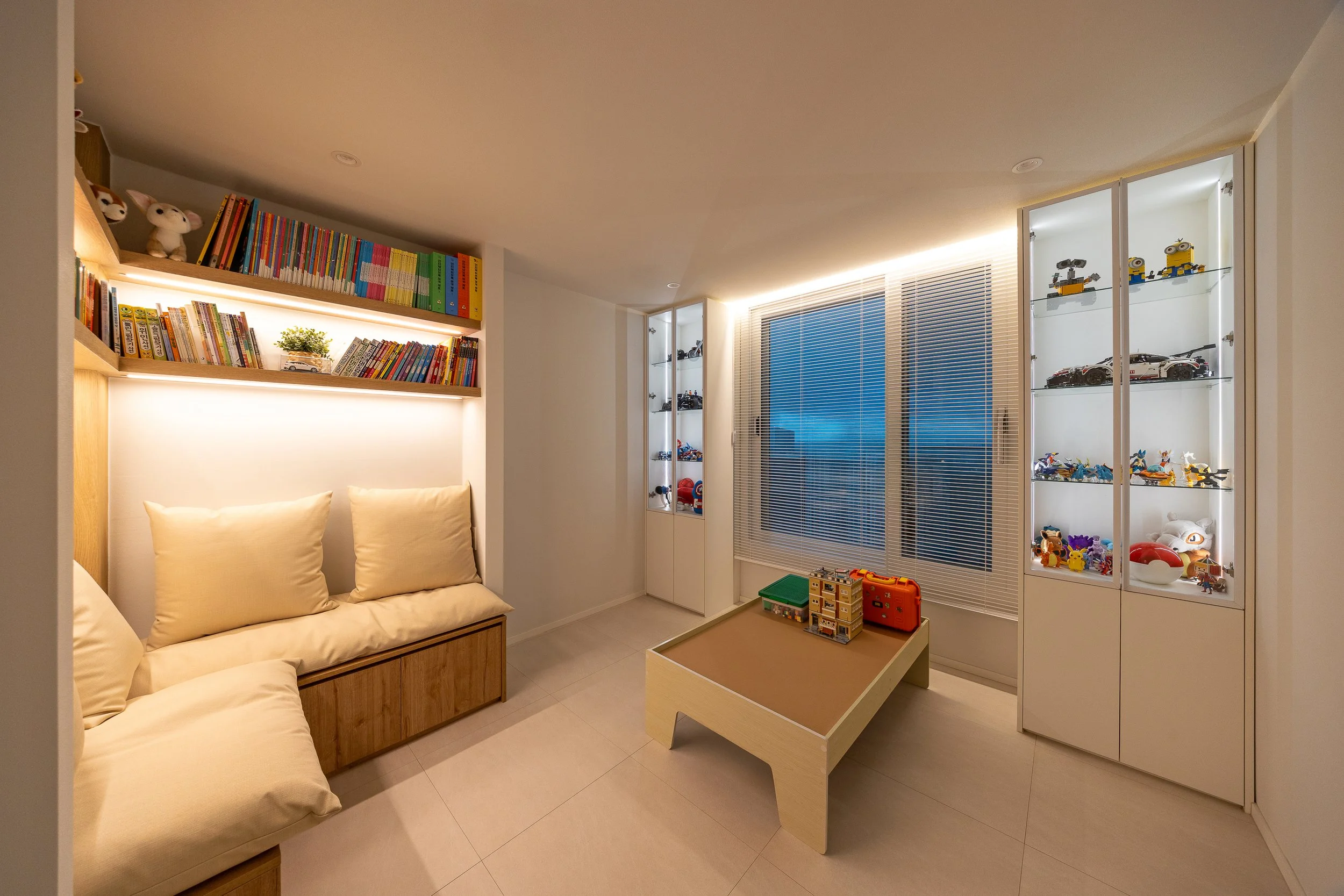 Modern children's playroom with built-in bookshelf, toy display cabinets, and a small table with toys on it.