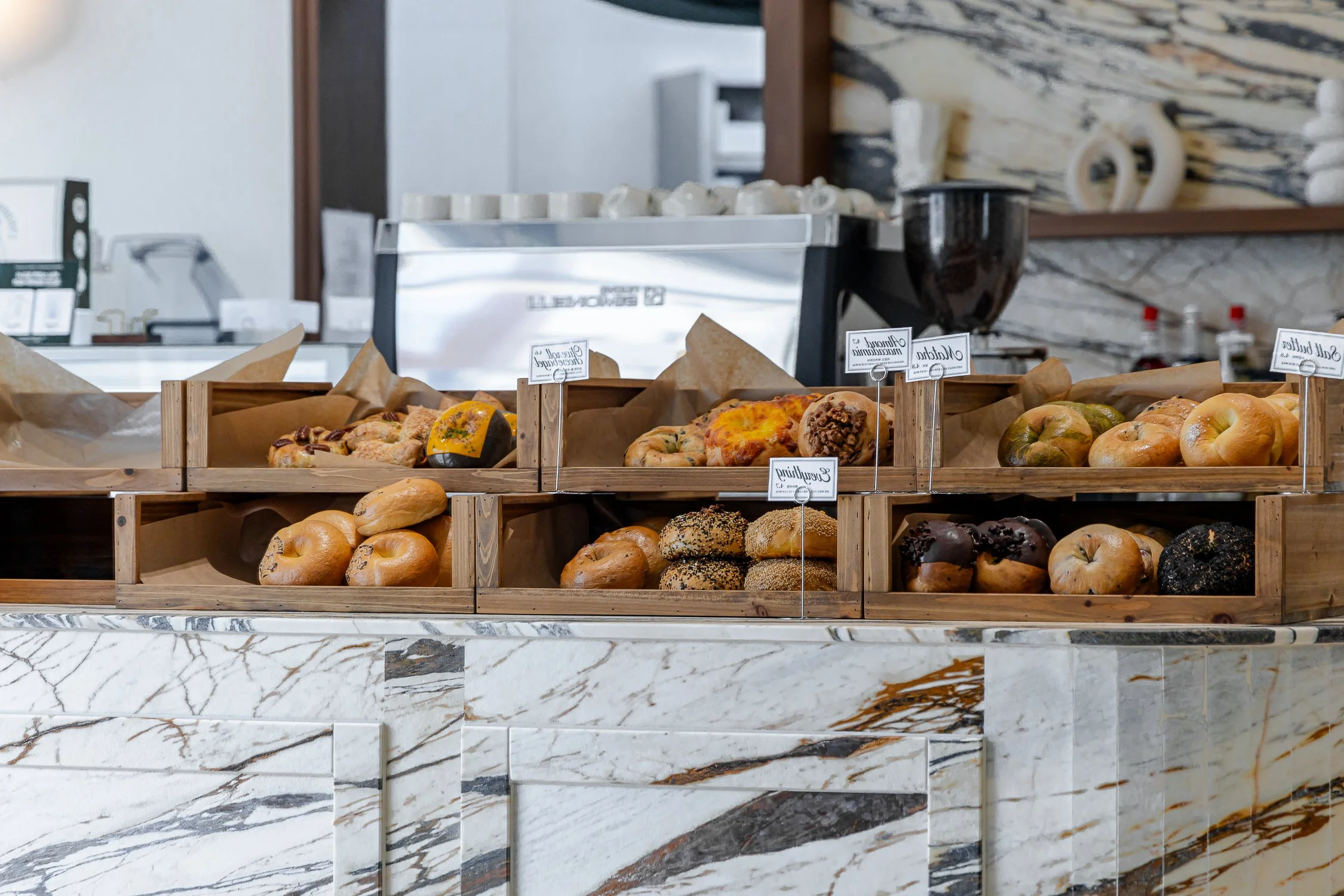 Assorted baked goods displayed in wooden trays at a bakery counter.