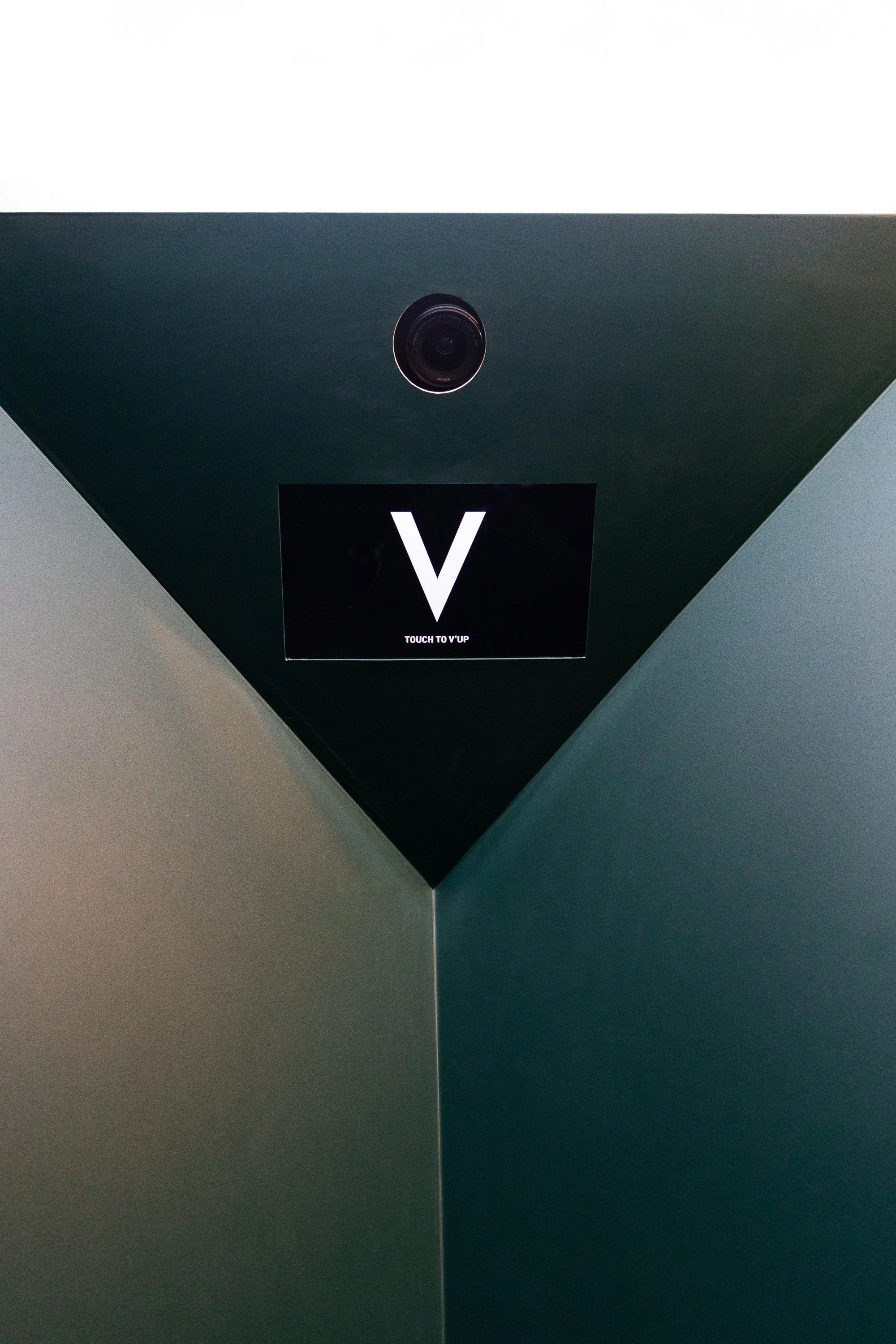 Ceiling with a camera and a display screen showing a large letter 'V'.