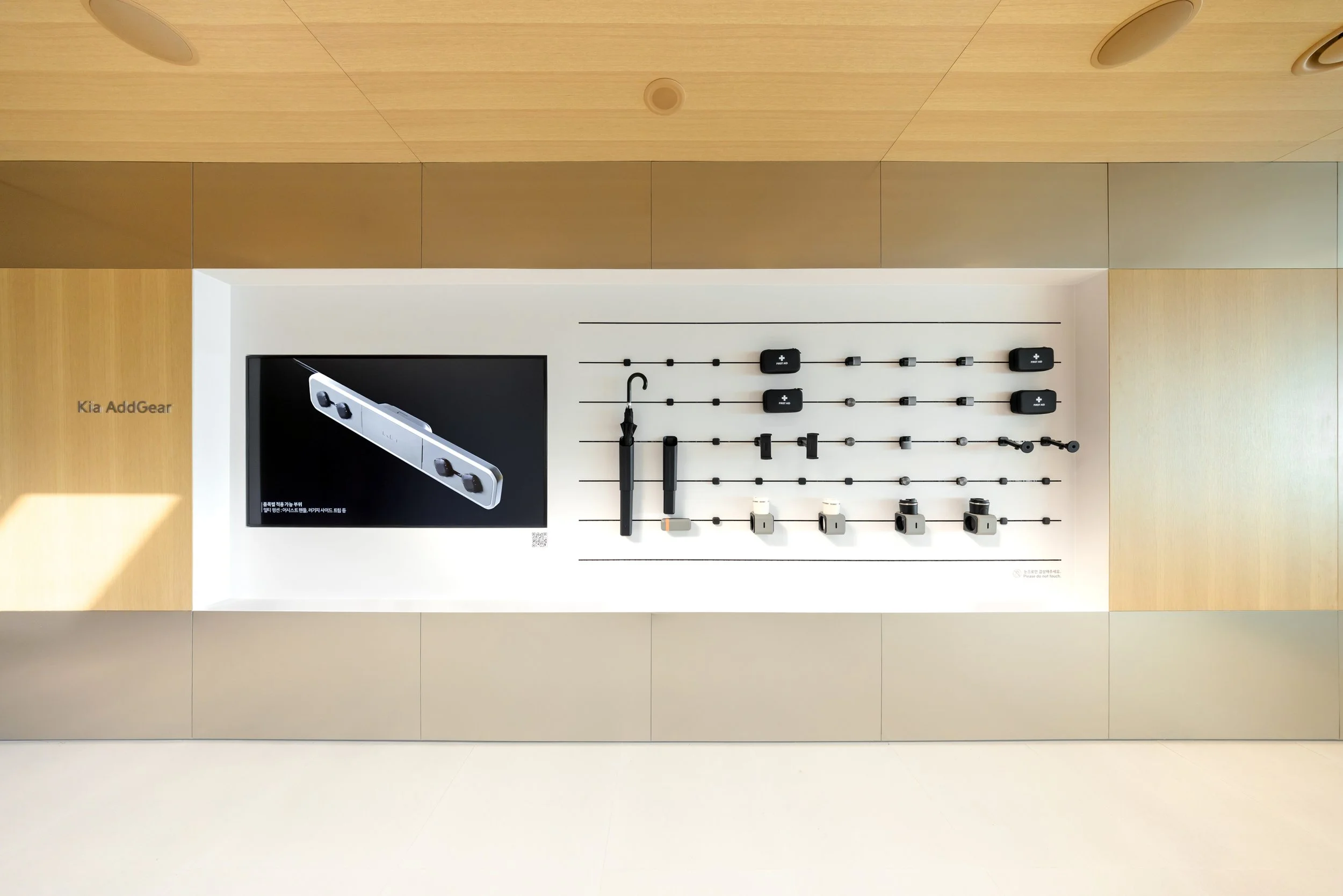 Display of Kia AddGear accessories, including cameras, mounts, and mounts with a digital screen showing product information, mounted on a wall.