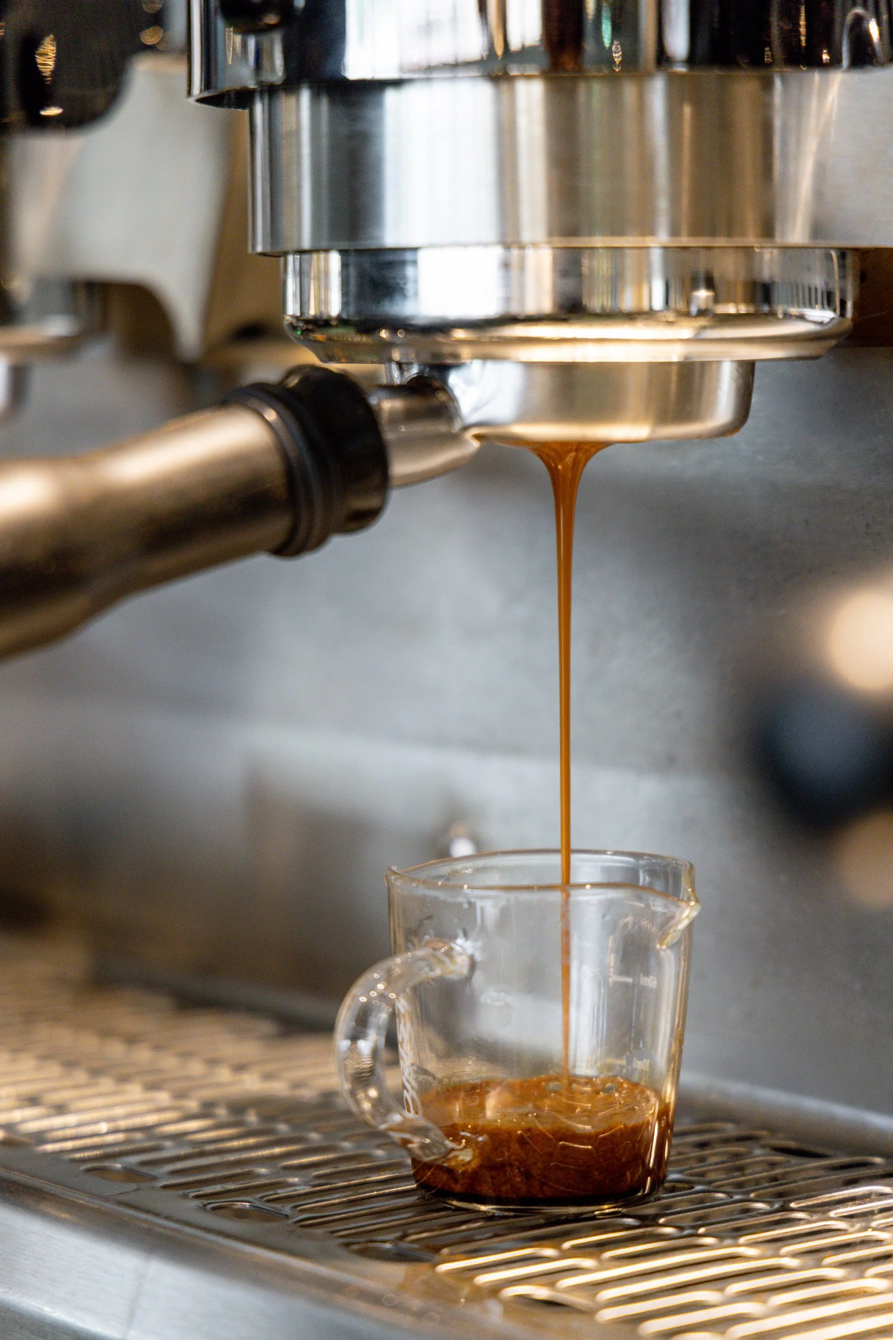 Close-up of espresso machine extracting coffee into a glass cup.